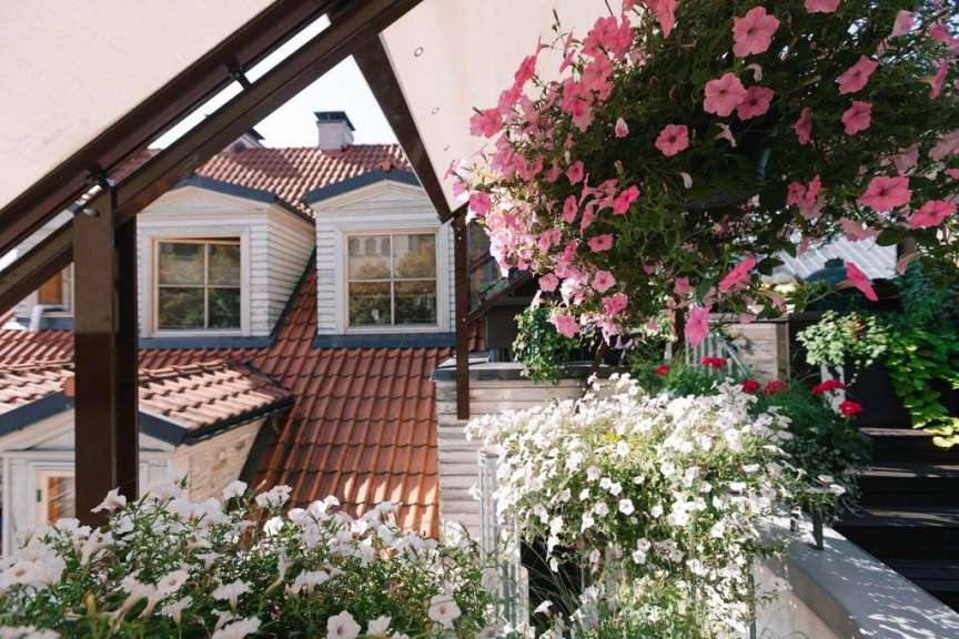 Ein Balkon mit rosa und weißen Blumen und einem Dach im Hintergrund