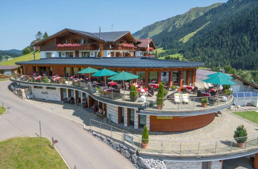 Ein Hotel mit Restaurantterrasse steht in den Bergen.