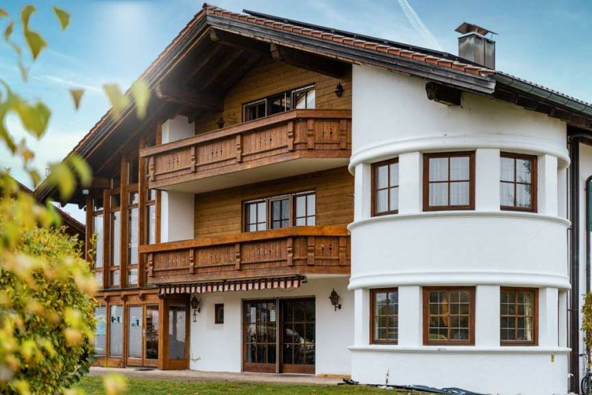 Ein weißes Haus mit einem Holzbalkon und vielen Fenstern