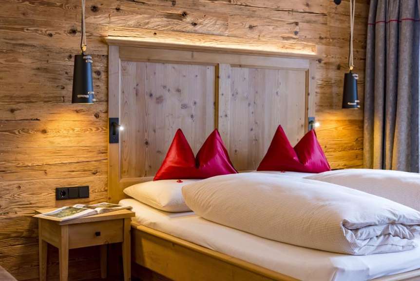 Ein modernes Schlafzimmer mit Holzwänden und einem bequemen Bett mit roten Kissen.