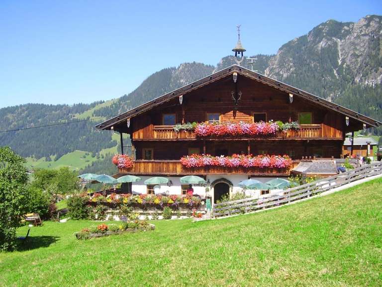 Ein großes Holzhaus mit Balkonen voller Blumen und Sonnenschirmen
