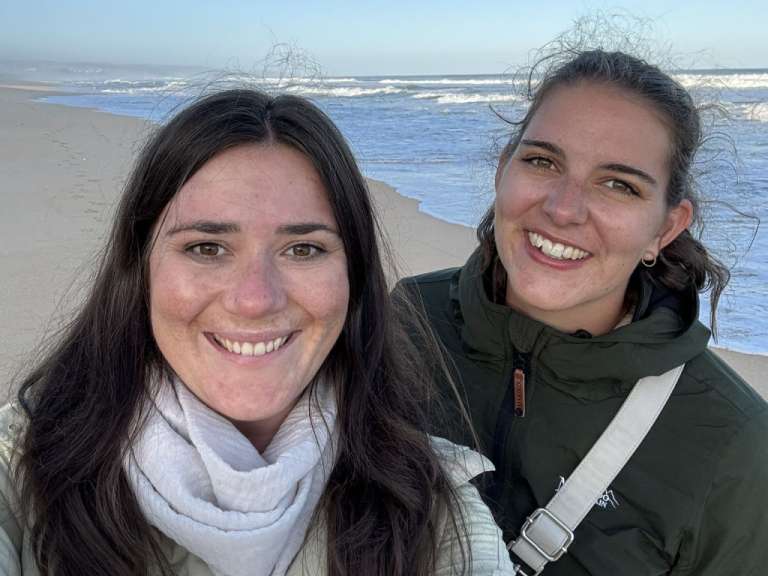 Zwei junge frauen stehen am strand und lächeln