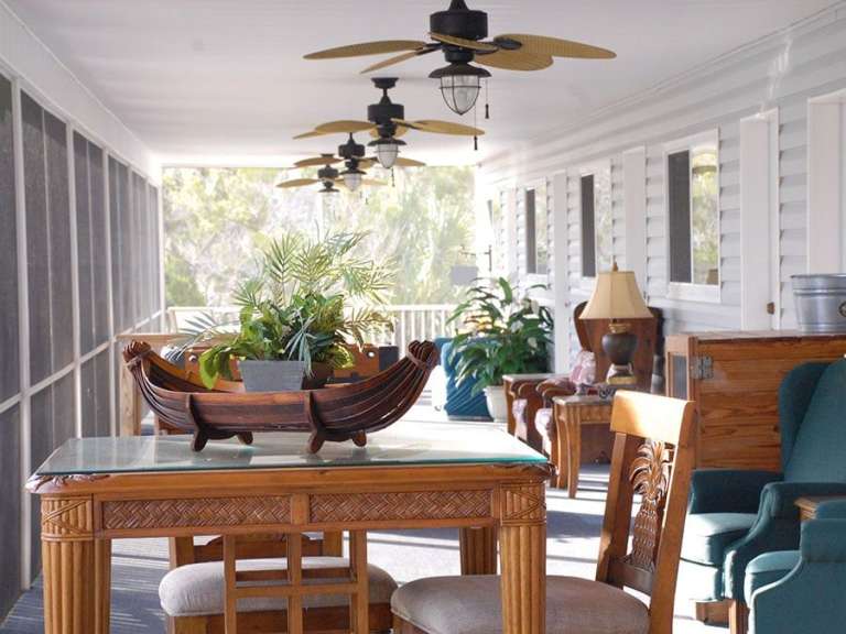 Eine Veranda mit Tisch und Stühlen und Deckenventilatoren