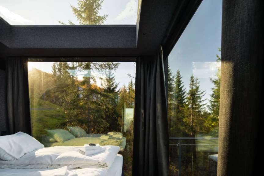 Ein Schlafzimmer mit einem Bett und einem Fenster mit Blick auf einen Wald
