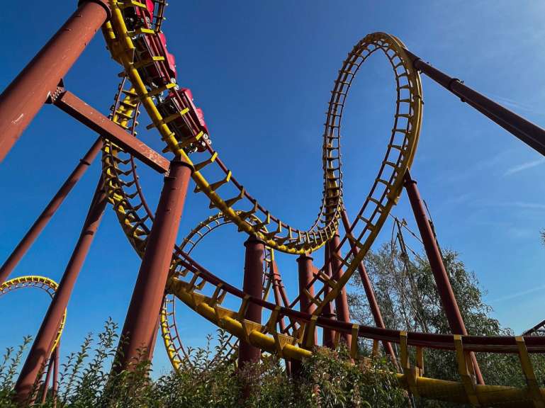 Eine Achterbahn in einem Park mit einem blauen Himmel dahinter