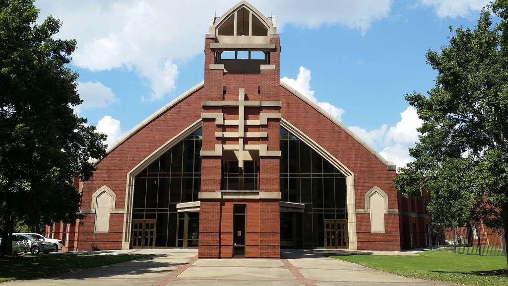 Eine rote Backsteinkirche mit einem Glockenturm und einem Kreuz darauf