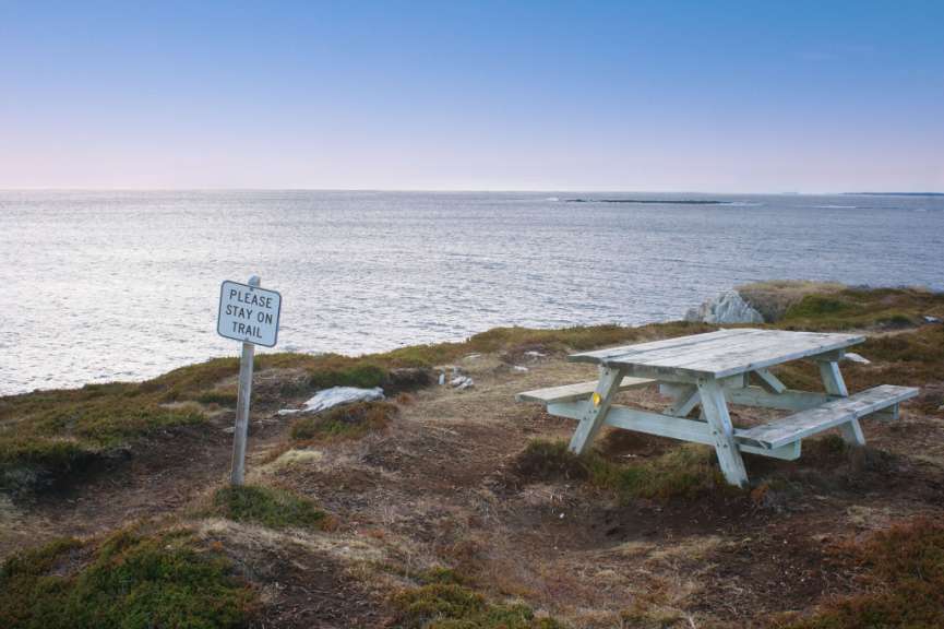 Ein Picknicktisch auf einem Hügel mit einem Schild, das sagt „ bitte stehen Sie auf dem Weg “