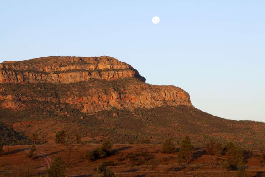 Ein voller Mond steigt über einen felsigen Berg
