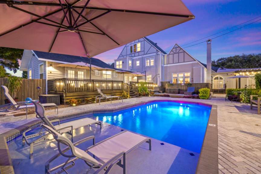 Ein großer Pool mit Liegestühlen und Sonnenschirmen in der Nähe eines Hauses