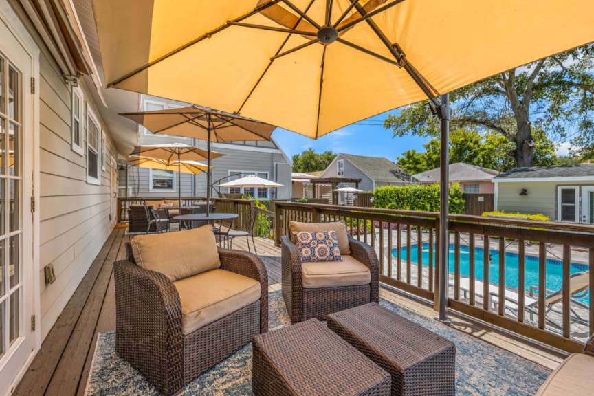 Ein Deck mit Stühlen und Tischen und Sonnenschirmen mit einem Pool im Hintergrund