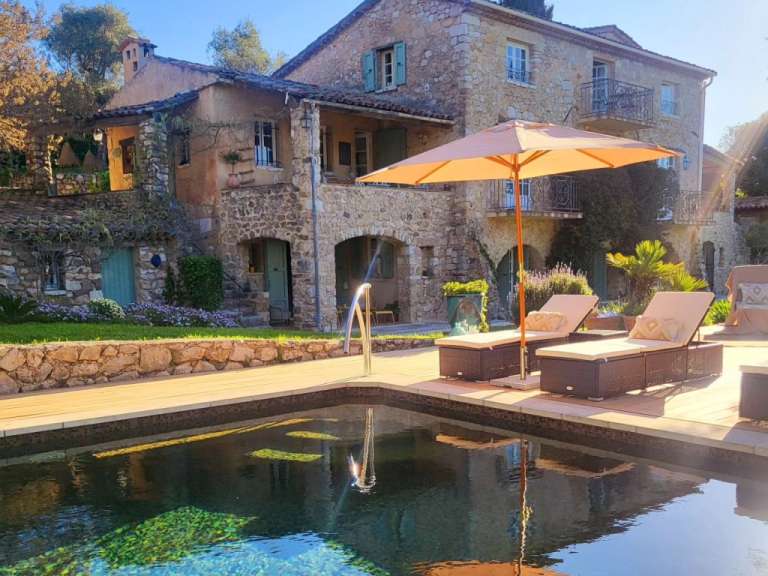 Ein Pool mit Liegestühlen und einem Sonnenschirm vor einem Steinhaus