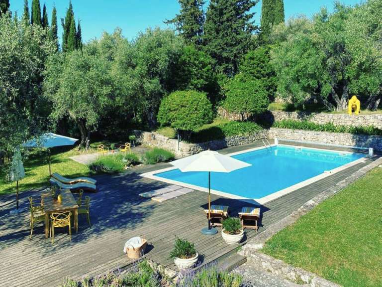 Ein großer Swimmingpool umgeben von Bäumen und einem Holzdeck