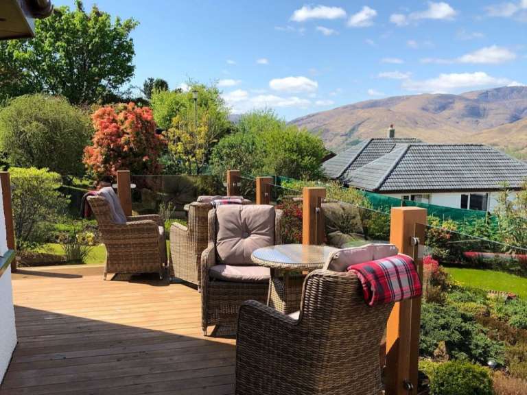 Ein Deck mit Stühlen und einem Tisch und einem Haus im Hintergrund