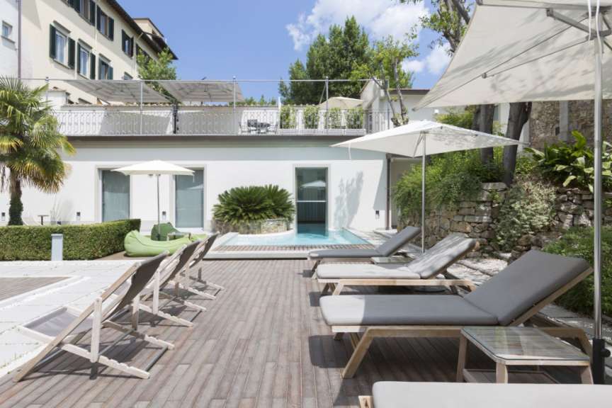 Eine Terrasse mit Liegestühlen und Sonnenschirmen neben einem Pool