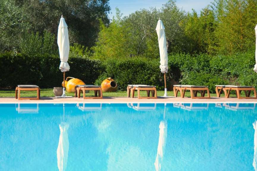 Ein Swimmingpool mit Liegestühlen und Sonnenschirmen umgeben