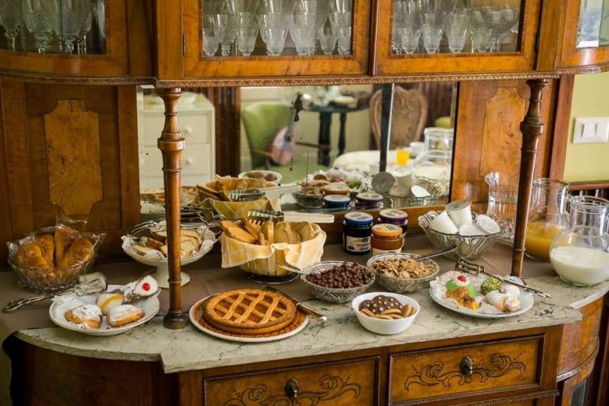 Ein Buffet mit Frühstücksspeisen wie Gebäck, Obst, Müsli und Marmelade steht auf einem Holzkonsolentisch.