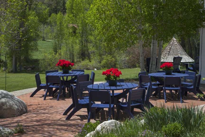 Eine Terrasse mit blauen Tischen und Stühlen und roten Blumen in Töpfen