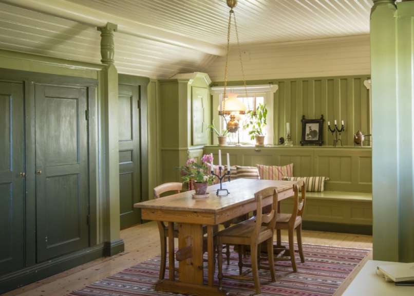 Ein Esszimmer mit einem Tisch und Stühlen und grünen Wänden