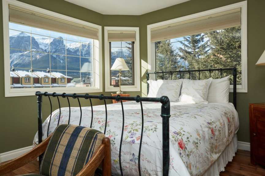 Ein Schlafzimmer mit einem Bett und zwei Fenstern mit Blick auf die Berge