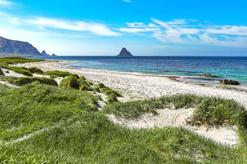 Ein weißer sandiger Strand mit einem Berg im Hintergrund