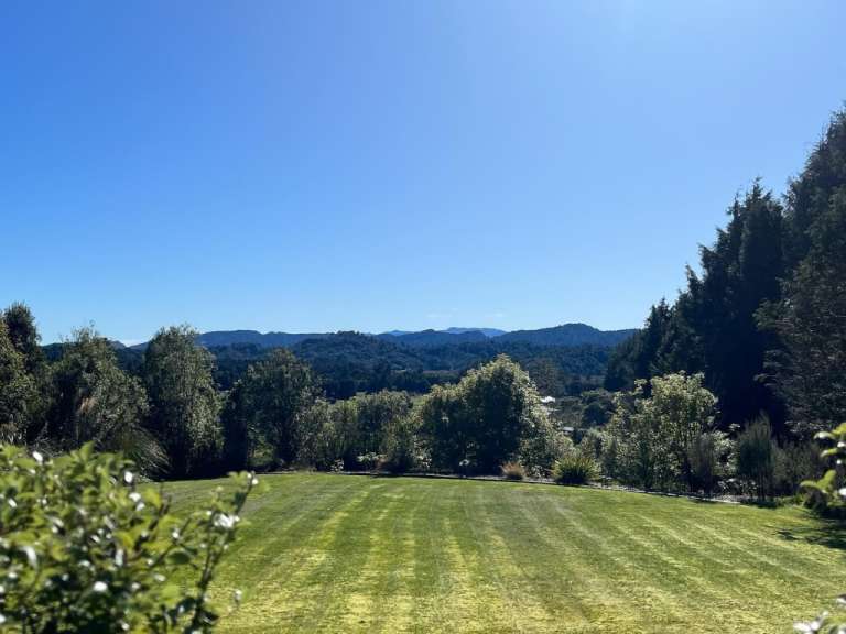 Ein großer grüner Rasen mit Bäumen und Bergen im Hintergrund