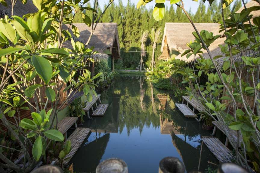 Ein Teich mit Bänken und Hütten im Hintergrund