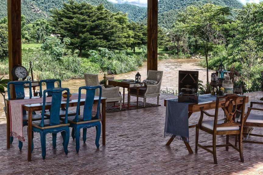 Ein Tisch und Stühle auf einer Terrasse mit Blick auf einen Fluss