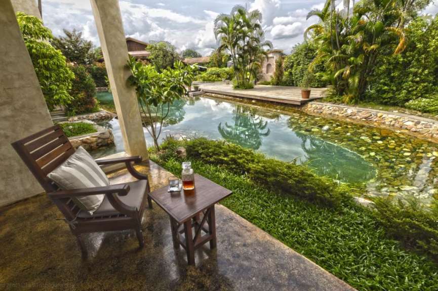 Ein Stuhl und ein Tisch mit einer Flasche auf einem Tisch neben einem Pool