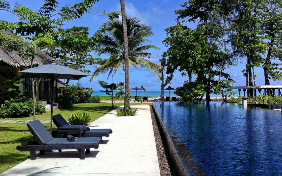 Liegestühle und Sonnenschirme stehen neben einem Infinity-Pool