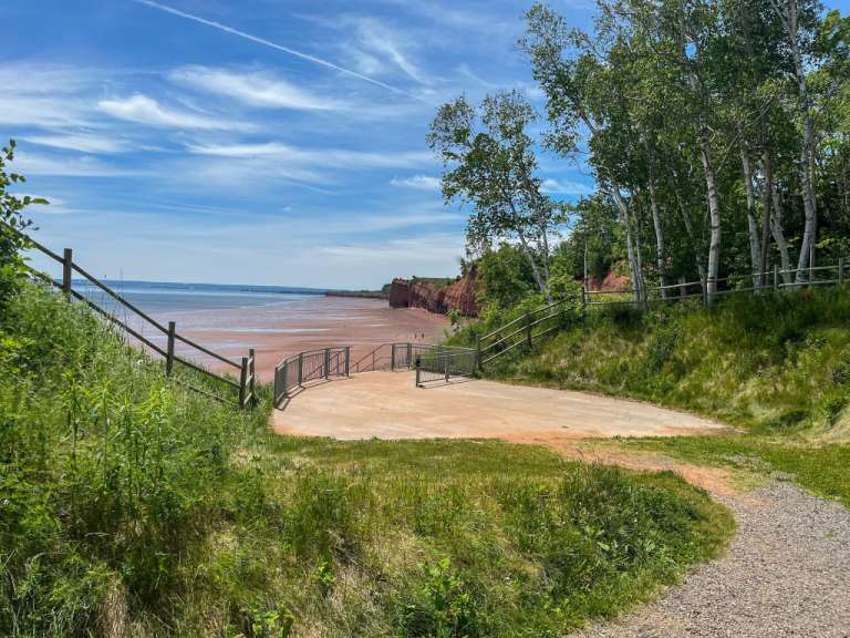 Eine Treppe führt hinunter zu einem Strand mit rotem Sand