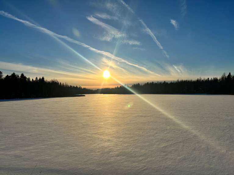 Die Sonne geht über einem schneebedeckten Feld