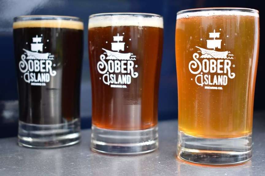 Drei Gläser mit der Aufschrift sober island stehen nebeneinander