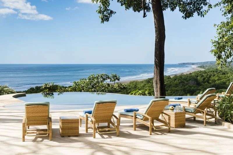 Liegestühle stehen neben einem Infinity-Pool mit Blick auf das Meer .