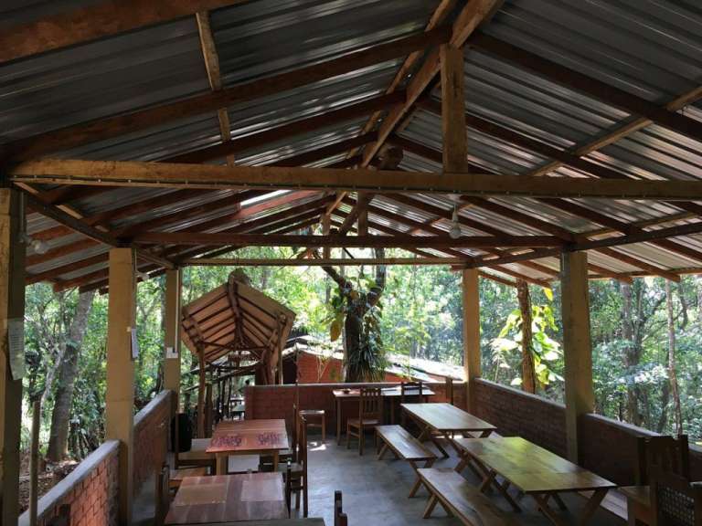 Ein Restaurant mit Holztischen und Stühlen unter einem Metalldach