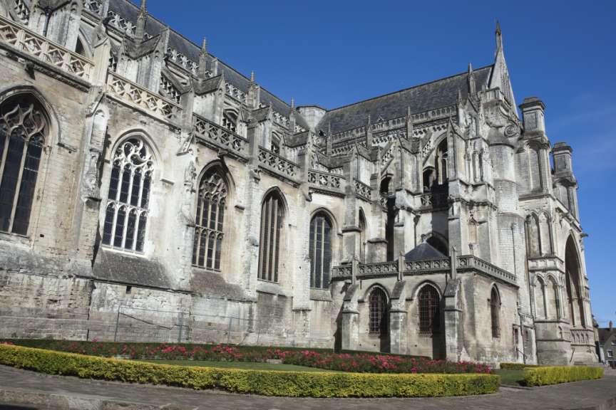 Ein detaillierter Blick auf die steinernen Details einer gotischen Kathedrale unter einem strahlend blauen Himmel.