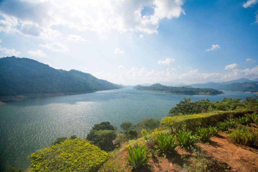 Ein großer See umgeben von Bergen und Bäumen an einem sonnigen Tag