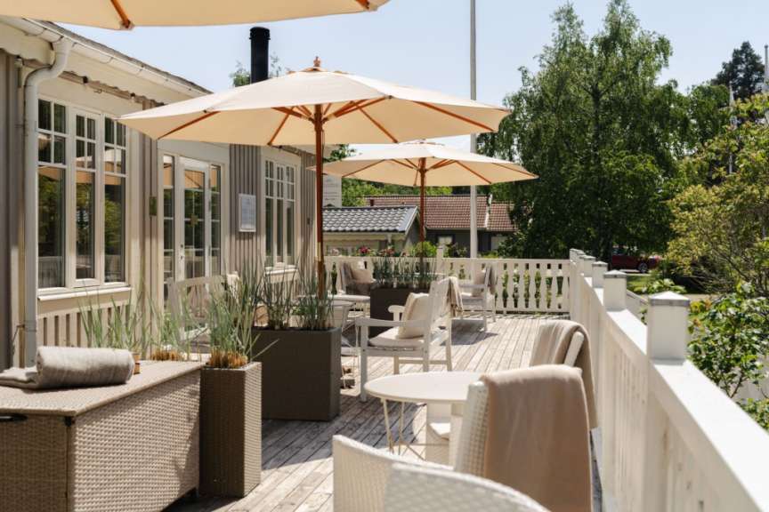 Ein Deck mit Tisch und Stühlen und Regenschirmen an einem sonnigen Tag