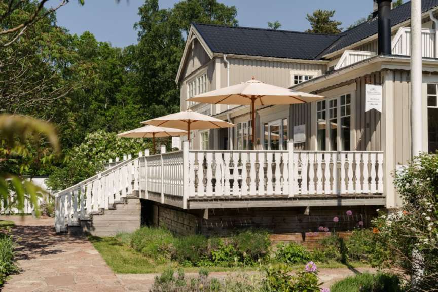 Ein Haus mit einer weißen Veranda und zwei Sonnenschirmen