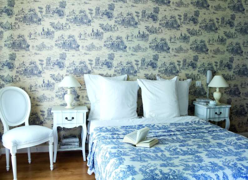 Ein Schlafzimmer mit blau-weißer Tapete und einem Bett