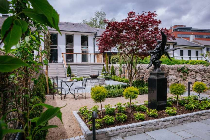 Ein Garten mit einem Tisch und Stühlen und einer Statue