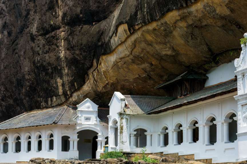 Ein weißes Gebäude steht unter einem großen Felsen