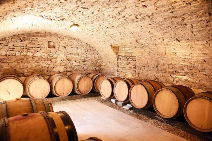Eine Reihe von Holzfässern in einem Keller mit Steinwänden