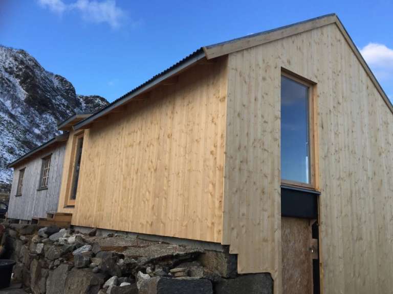 Ein Holzgebäude mit einem Fenster und einem Berg im Hintergrund