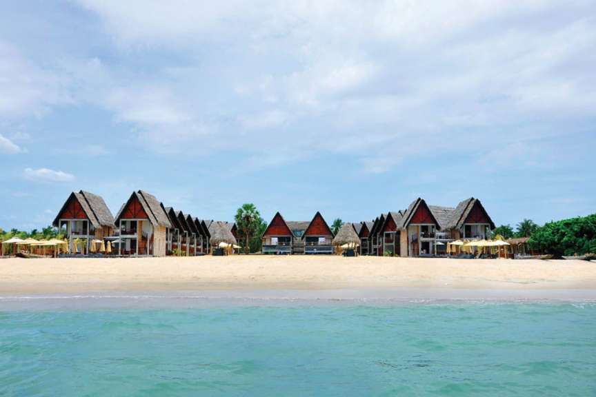 Ein Strand mit vielen Hütten und Sonnenschirmen