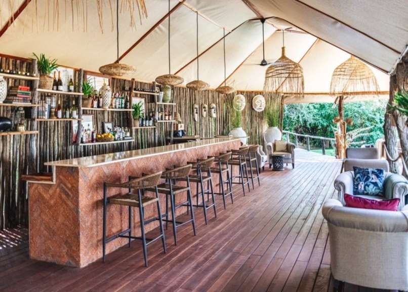 Eine lange Bar mit Stühlen und Regalen in einem Zelt