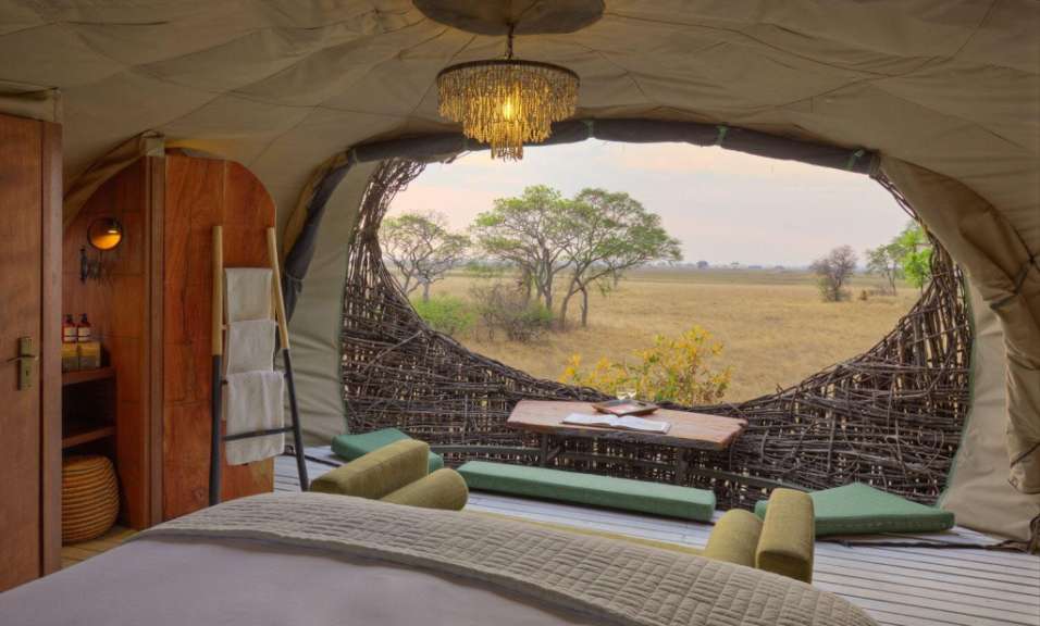 Ein Zimmer mit einem Bett und einem Tisch mit Blick auf eine Wiese