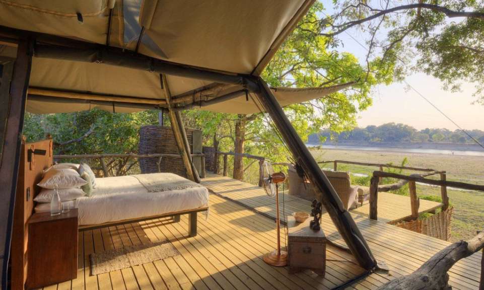 Ein Bett sitzt auf einem Holzdeck mit Blick auf einen Fluss