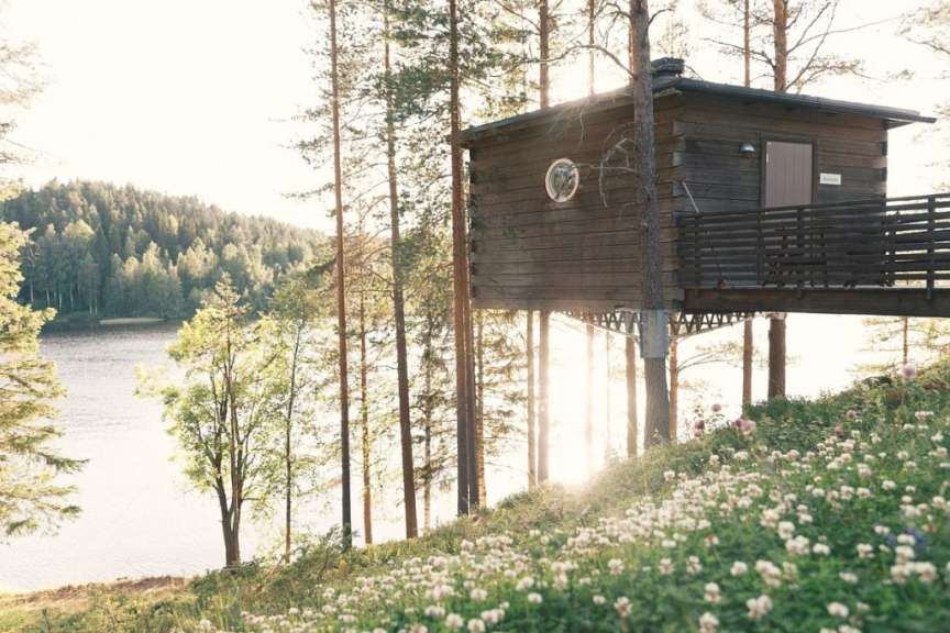 Ein kleines Holzhaus steht auf einem Hügel mit Blick auf einen See