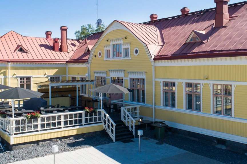 Ein gelbes Gebäude mit einem roten Dach und vielen Fenstern