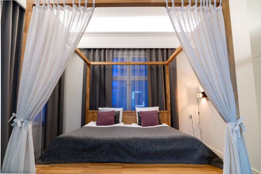 Ein Schlafzimmer mit Himmelbett und lila Kissen